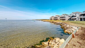 A waterfront property with clear water, a rocky shoreline, and multiple houses with balconies. - Great sound view waterfront home with private hot tub, AC, W/D & pool access (Avon)