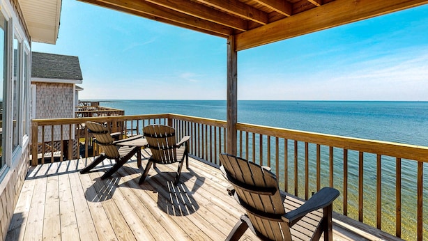 A wooden deck with chairs overlooking a body of water. - Great sound view waterfront home with private hot tub, AC, W/D & pool access (Avon)