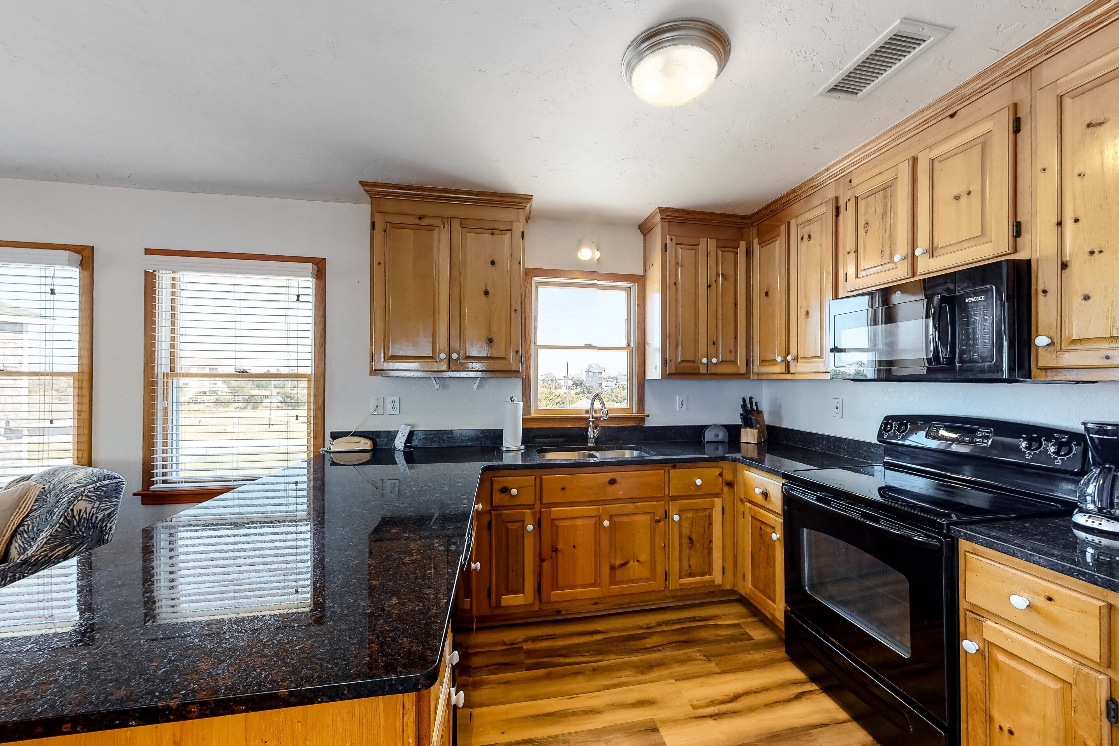 A kitchen with wooden cabinets, a black stove, and a granite countertop.