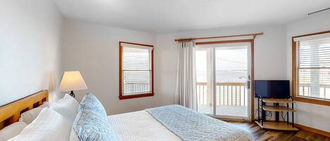A bedroom with a bed, a TV, and a balcony.