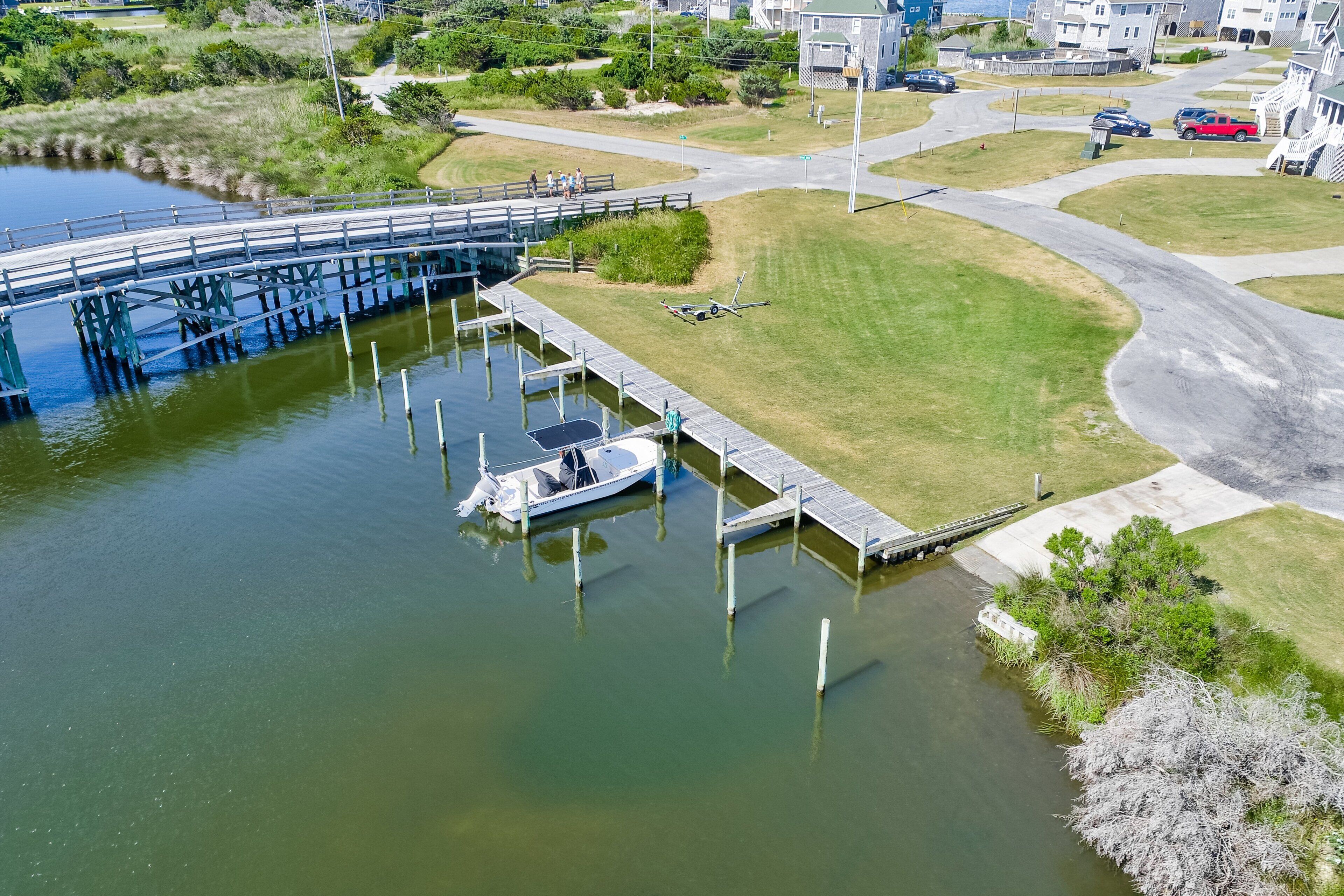 A marina with a dock, a small boat, and a bridge over water.