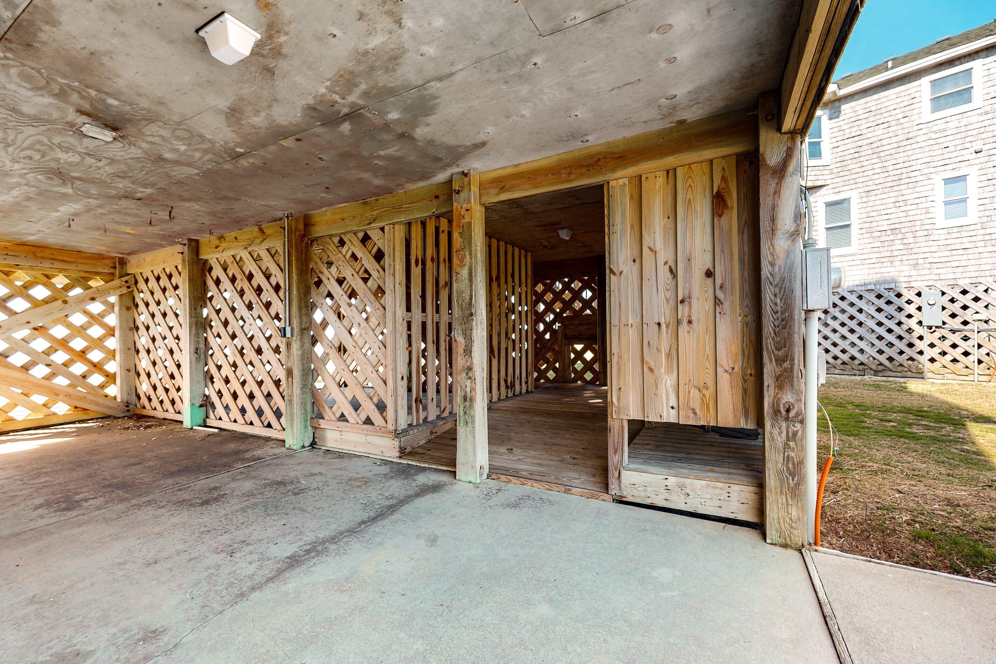 An outdoor covered patio area with wooden lattice panels and a concrete floor.