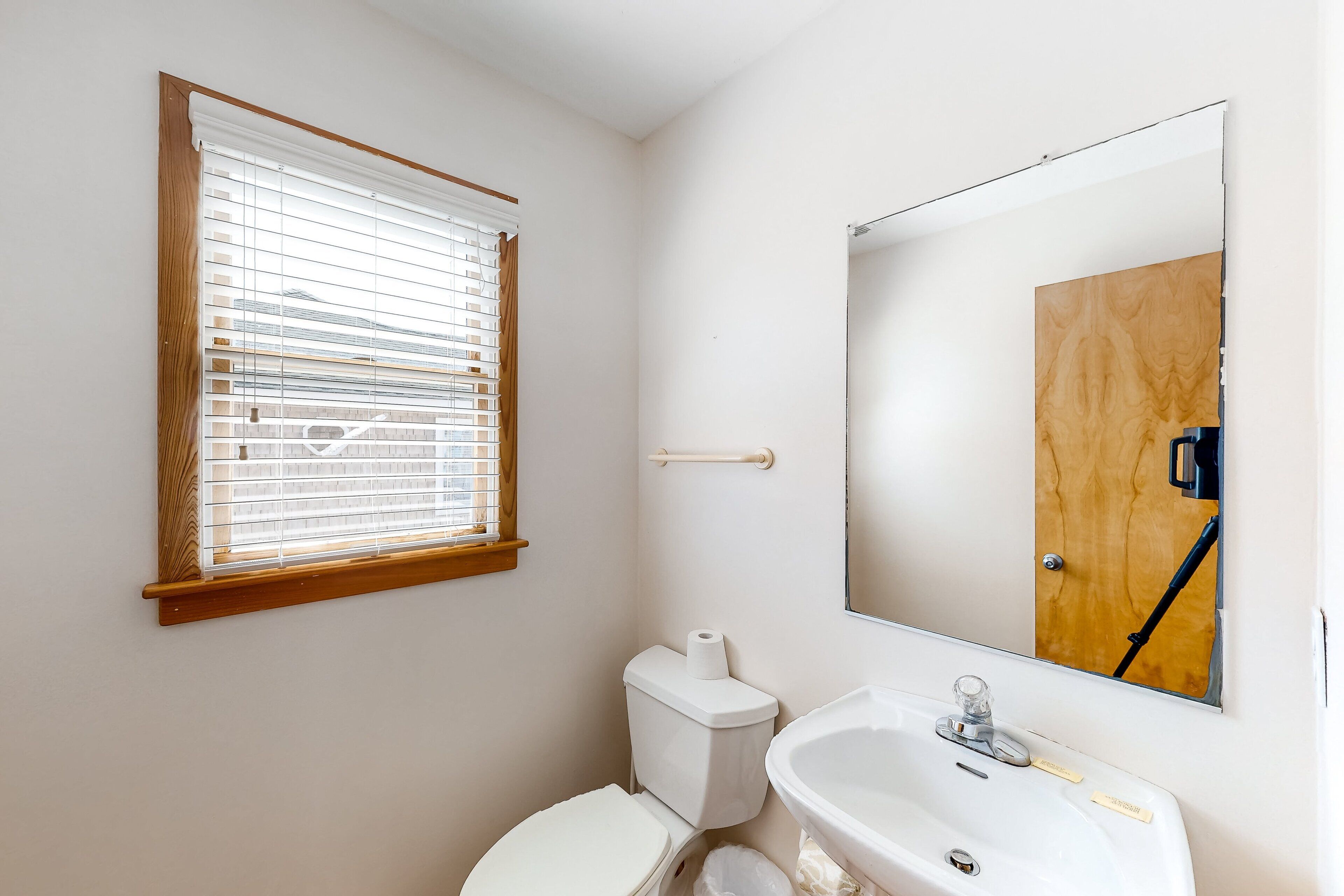 Baño con inodoro, lavabo y ventana con persianas.