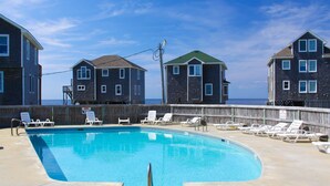 A swimming pool with lounge chairs and a wooden deck, overlooking the ocean. - Great sound view waterfront home with private hot tub, AC, W/D & pool access (Avon)
