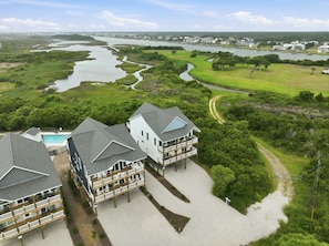 A coastal hotel with multiple balconies, a swimming pool, and a view of a river and greenery.