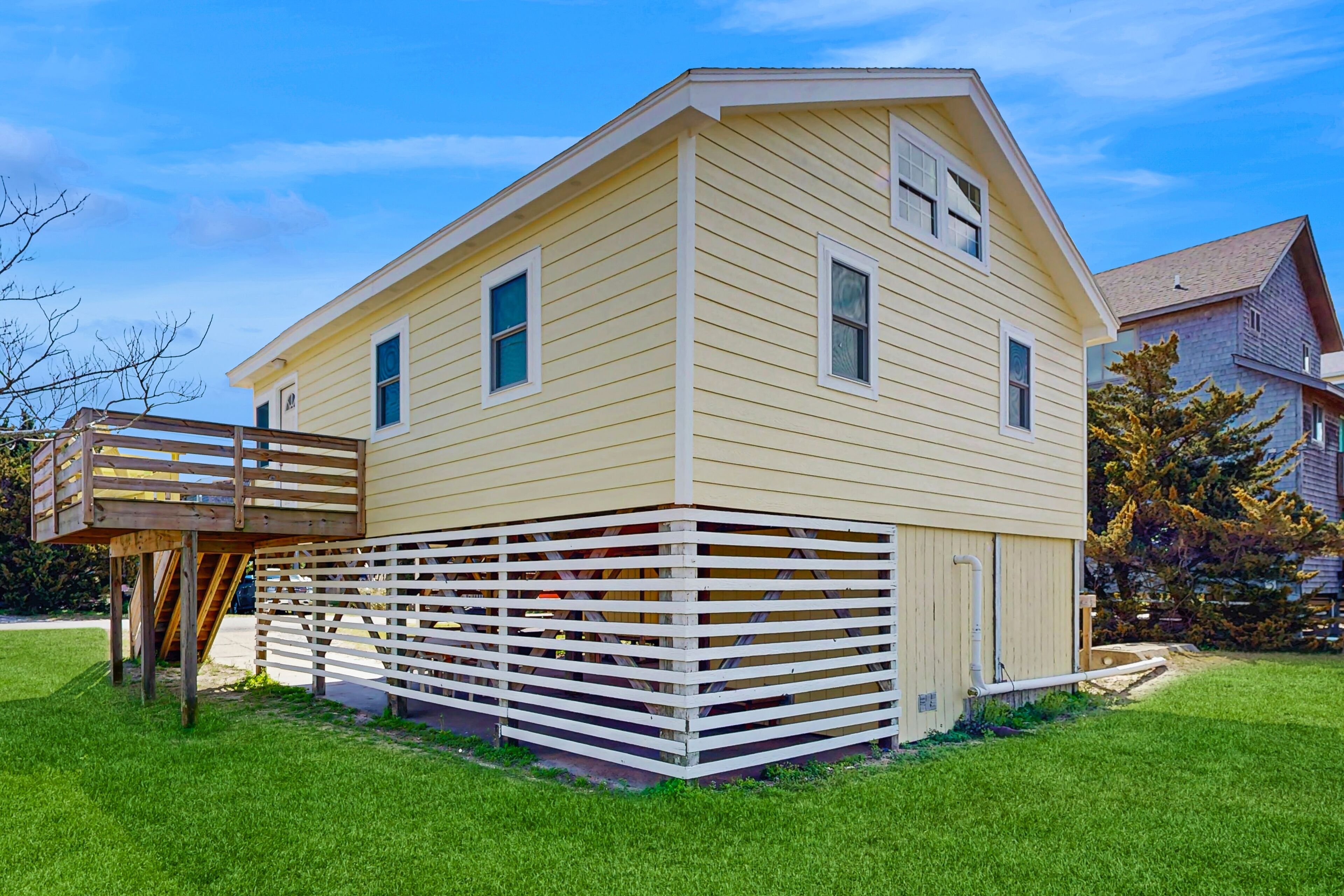 A two-story house with a wooden deck and a fenced area.