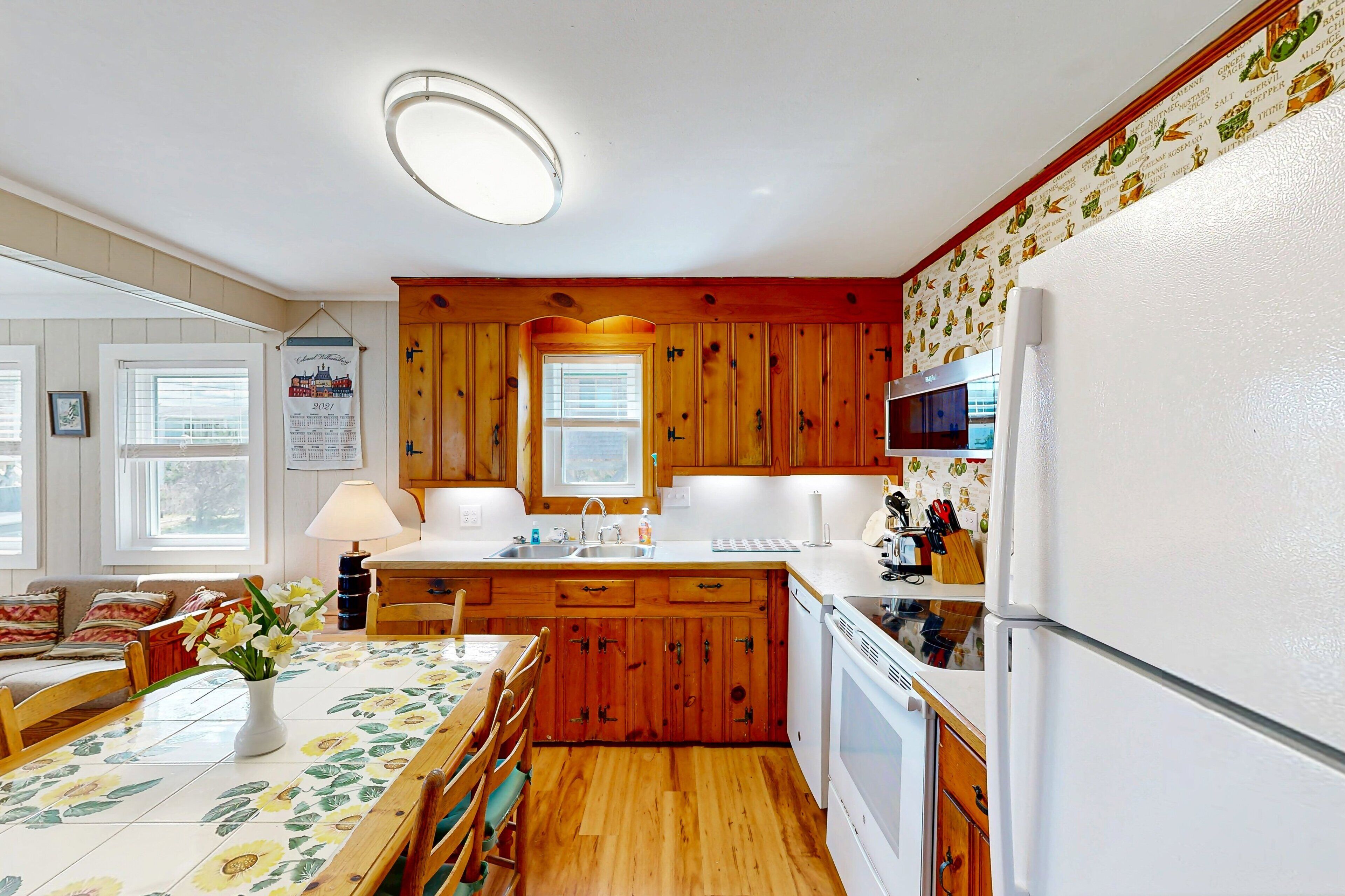 A kitchen with wooden cabinets, a white refrigerator, and a dining area with a table and chairs.