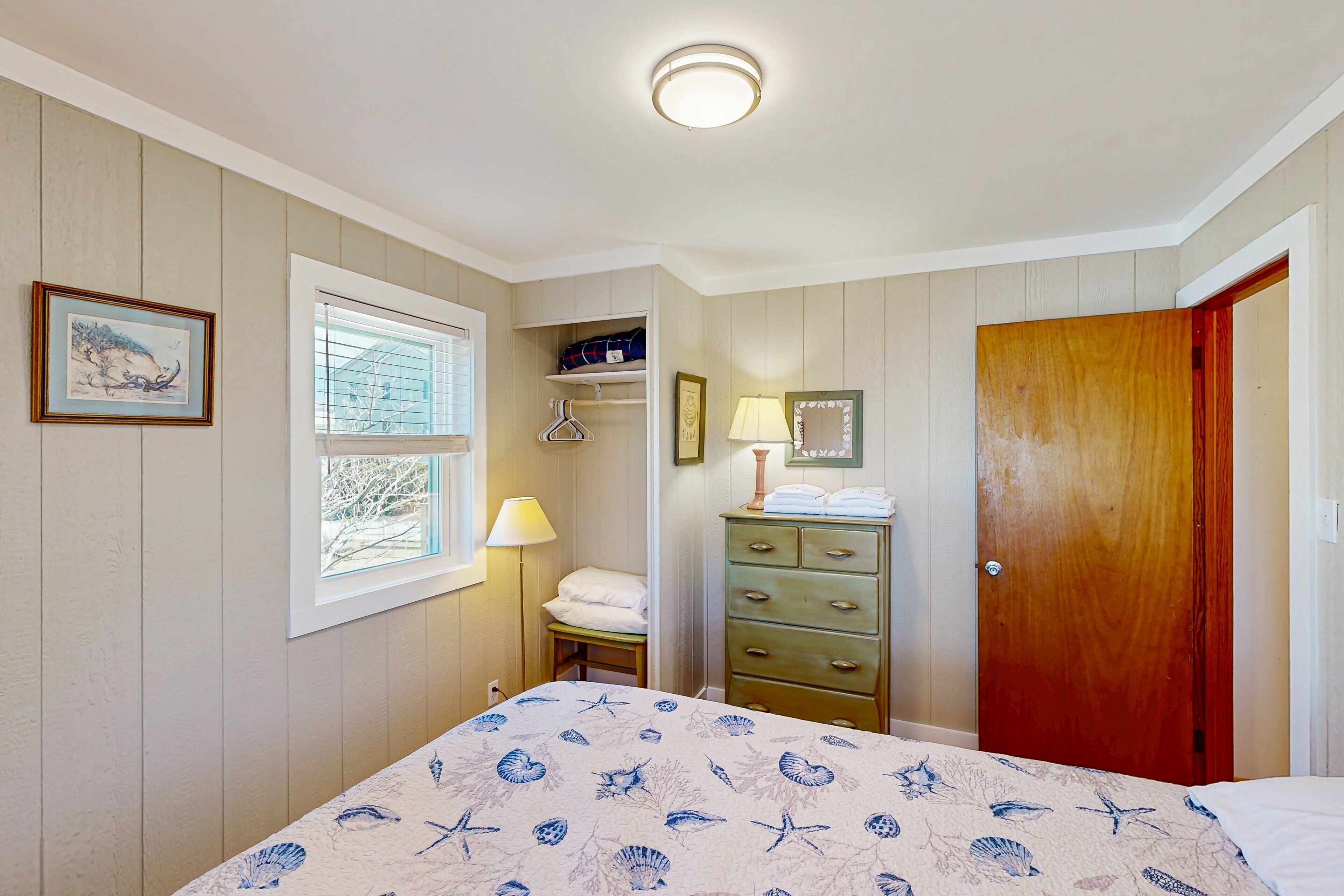 A bedroom with a bed, a dresser, a window, and a door.