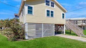 Ein zweigeschossiges Haus mit überdachter Veranda und einer Holztreppe, die darauf führt.