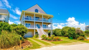 Ein zweistöckiges Haus mit Balkon, Veranda und Auffahrt.