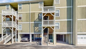 Un immeuble à plusieurs étages doté de balcons, d’un garage et d’un espace extérieur abrité.