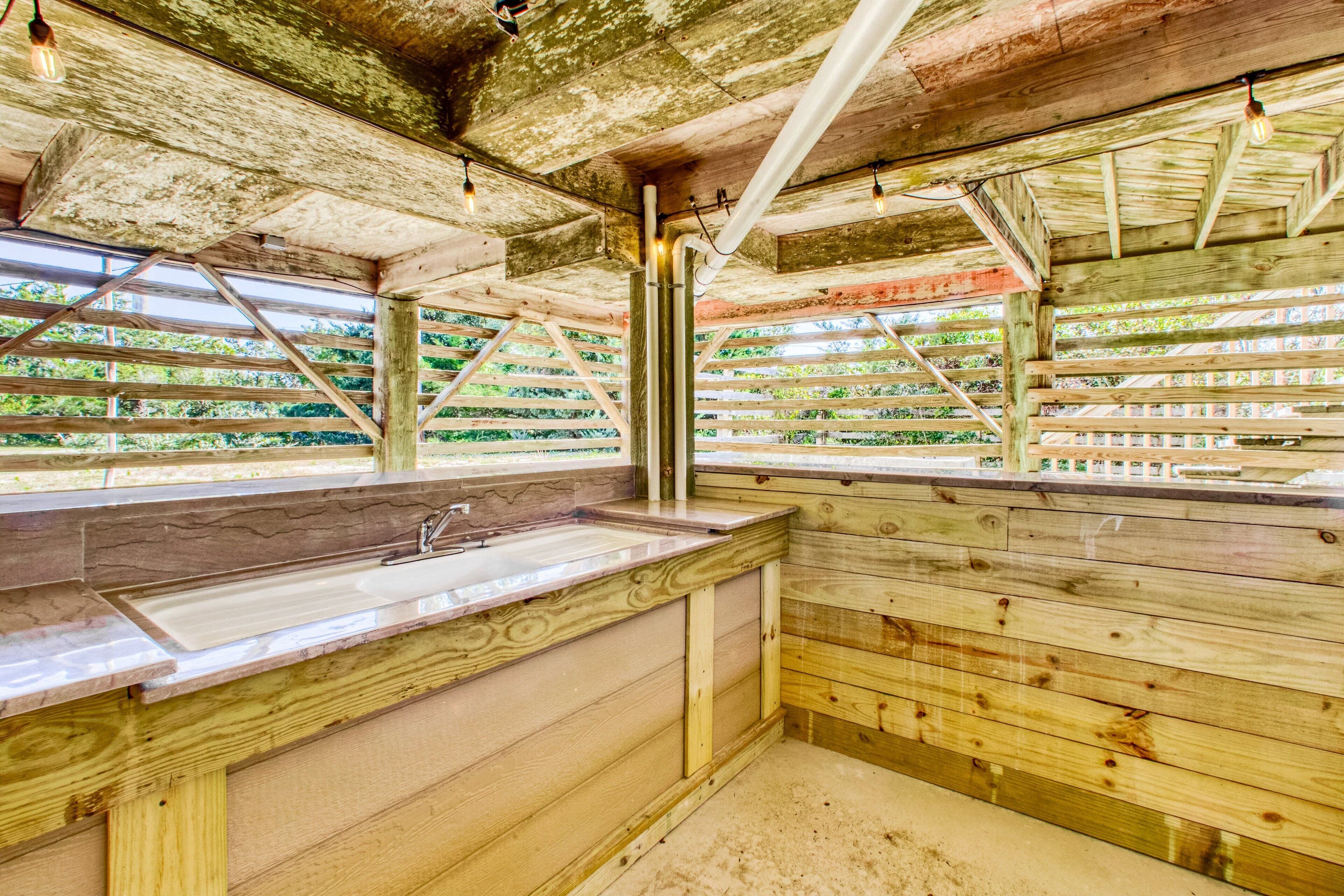 Un intérieur rustique en bois, avec un évier en pierre et des murs en bois, offrant une vue sur la verdure environnante.