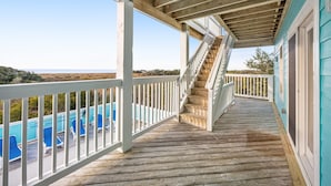 A wooden deck with a white railing, a staircase, and a view of a blue pool. - Sound front home with amazing views, private pool, hot tub, theater & rec room (Avon)