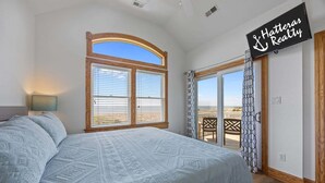 A bedroom with a large bed, a TV mounted on the wall, and a balcony with a view. - Sound front home with amazing views, private pool, hot tub, theater & rec room (Avon)