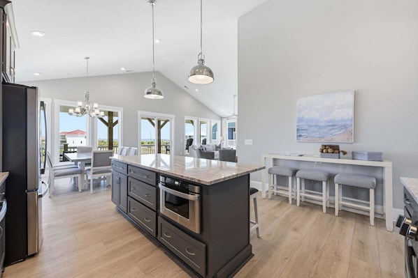 A modern kitchen with a central island, stainless steel appliances, and pendant lighting.