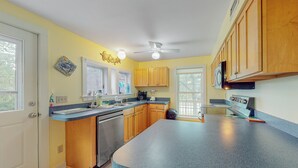 A kitchen with wooden cabinets, a granite countertop, a dishwasher, and a ceiling fan.