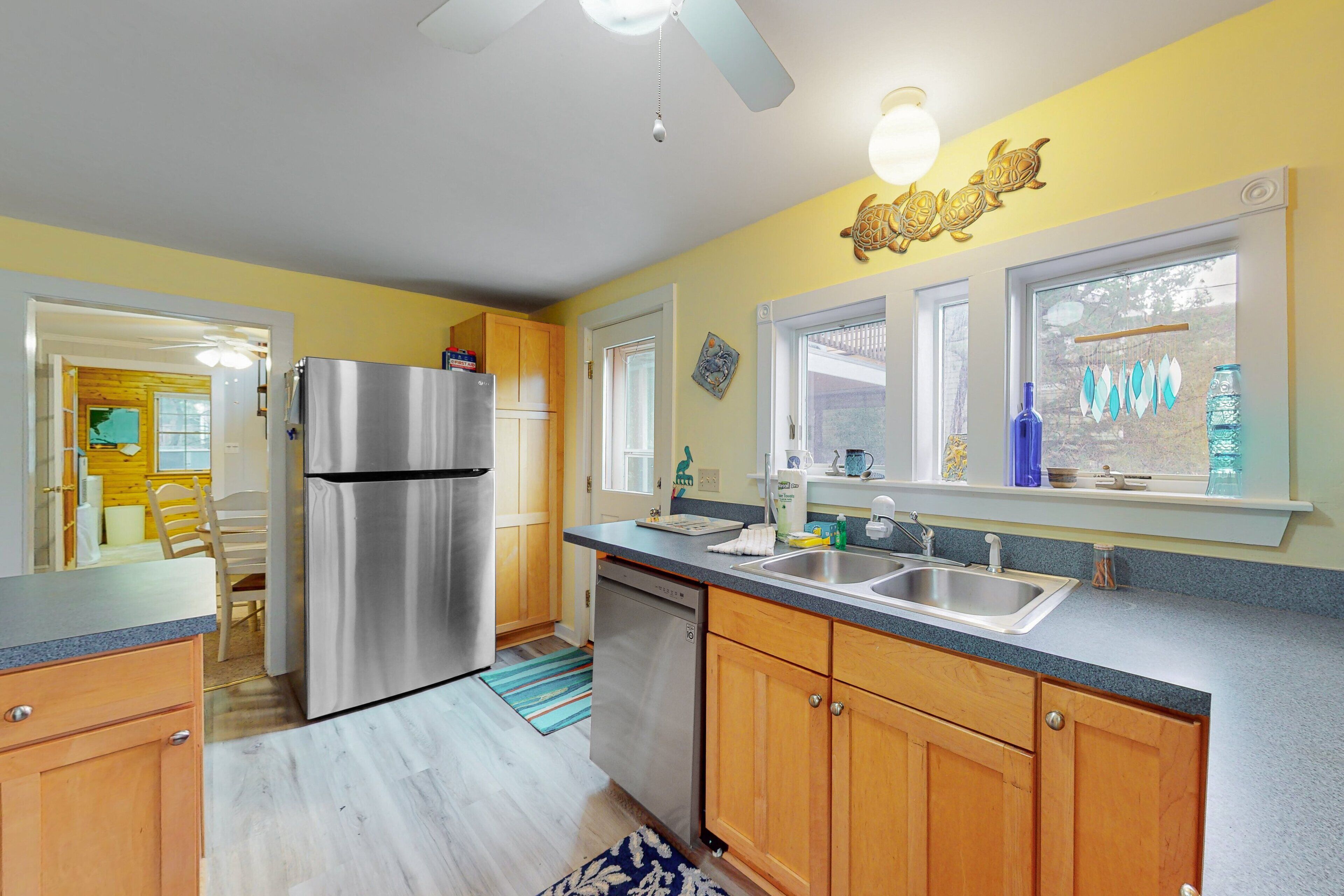 A modern kitchen with wooden cabinets, stainless steel appliances, and a window with decorative items.
