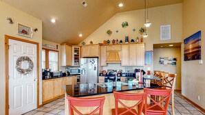A kitchen with wooden cabinets, a large island with bar stools, and decorative wall art. - 3-story luxury home with pool, hot tub, AC, tennis, & deck - dog-friendly (Avon)