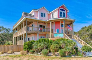 A two-story house with a balcony, a staircase, and a flag.
