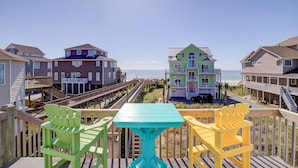A coastal view with colorful houses, a wooden deck, and a turquoise table. - Spacious, dog-friendly home with ocean views, beach access, & pool (North Topsail Beach)