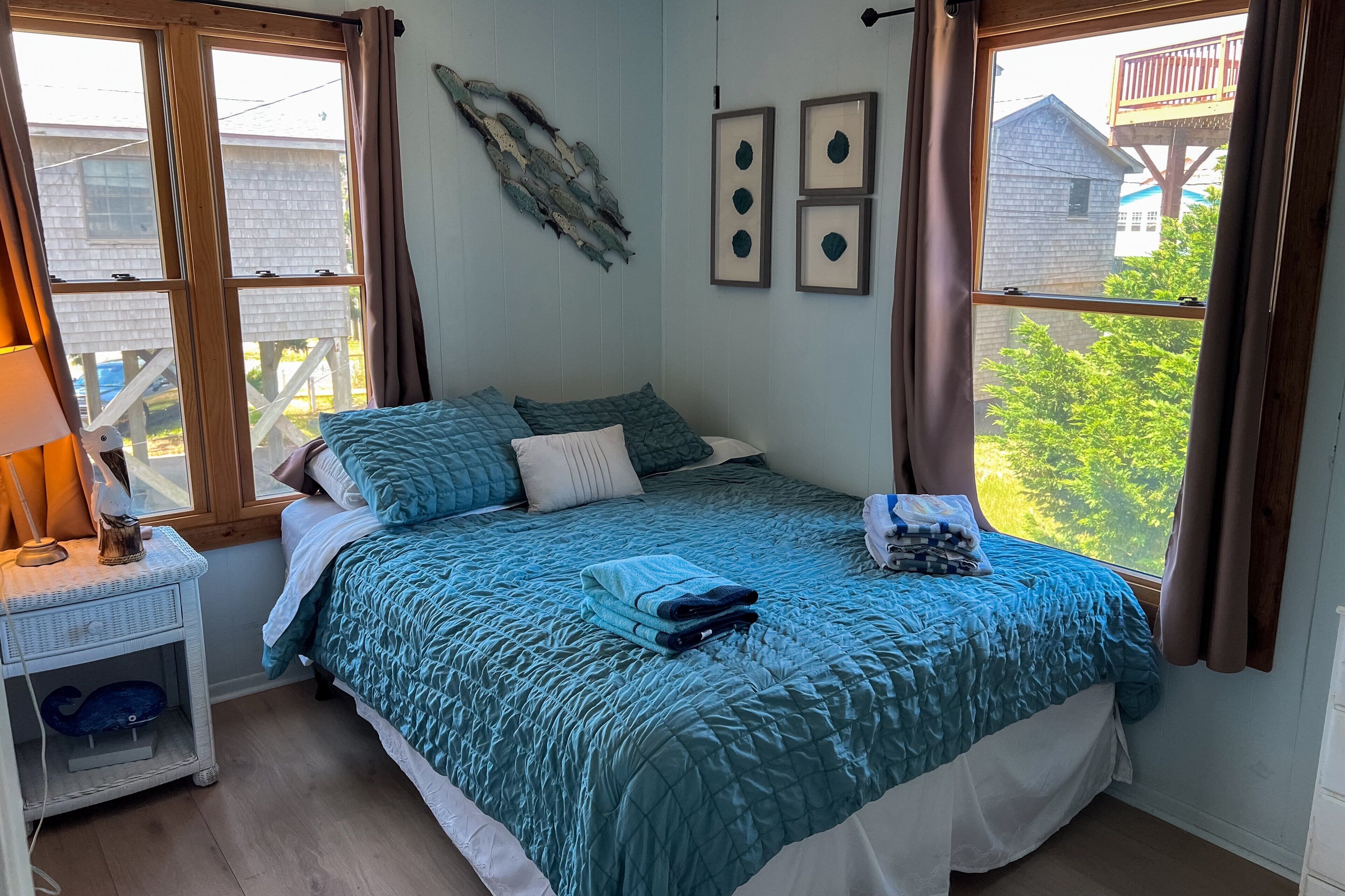 Ein Schlafzimmer mit einem Bett, einem Nachttisch, einem Fenster mit Vorhängen und einem Wandbild.