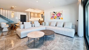 Ein modernes Wohnzimmer mit einem Ecksofa, einem runden Couchtisch und einem Esstisch.
