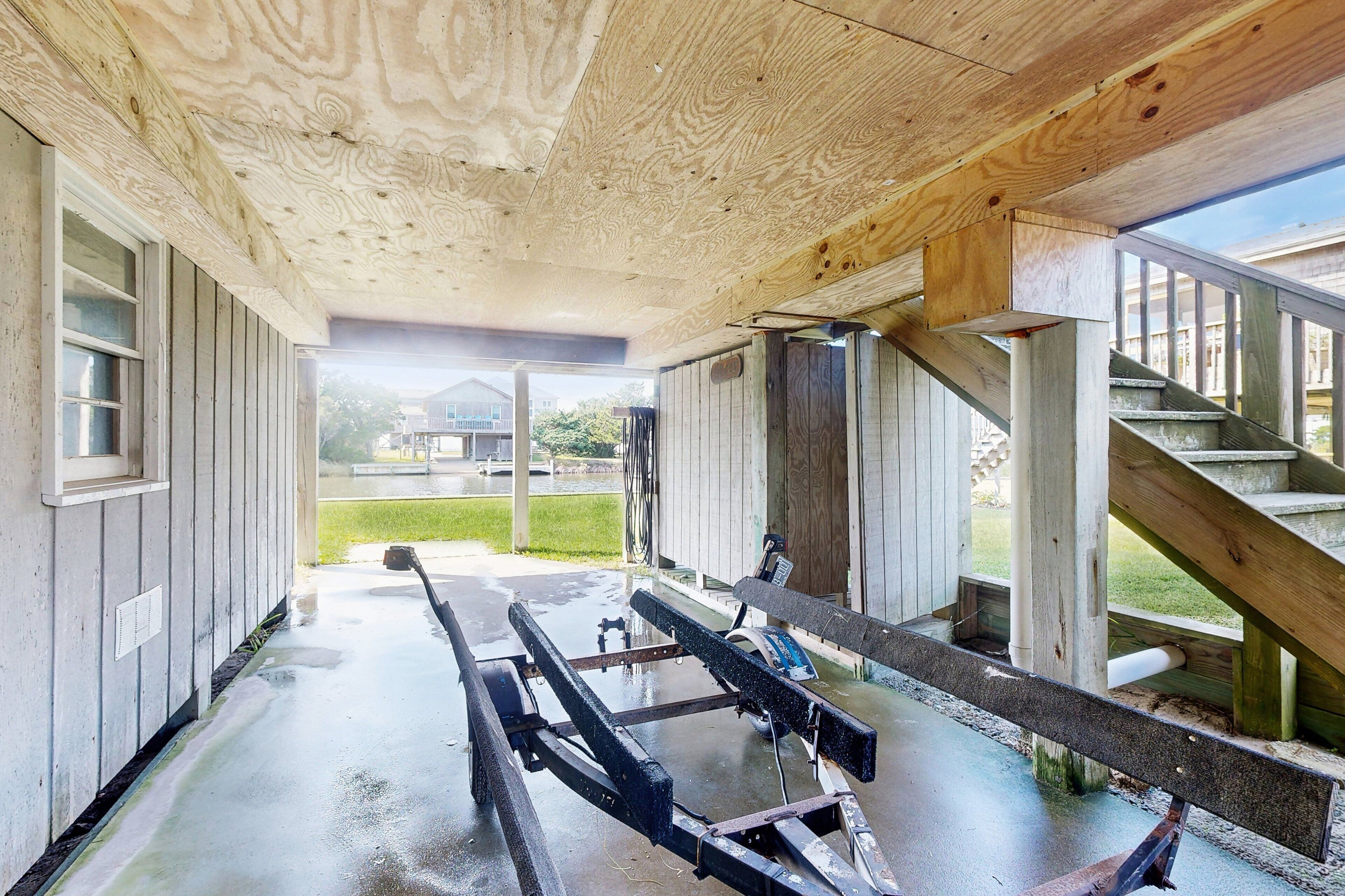A covered outdoor area with a wooden ceiling, a metal bench, and a staircase leading to a building.