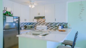 Una cucina moderna con mobili bianchi, frigorifero in acciaio inossidabile, forno a microonde e piano cottura.
