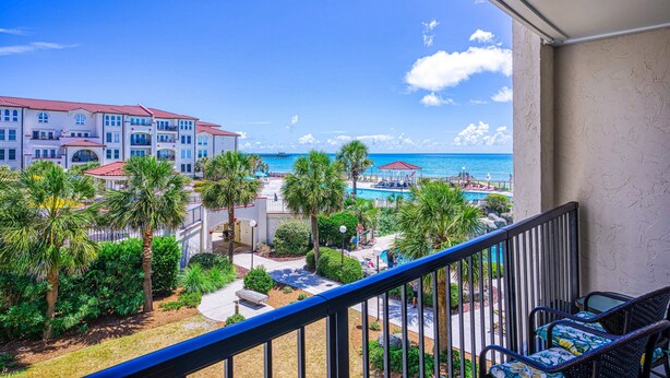 Un balcone con vista su un edificio alberghiero, una zona piscina e l'oceano.