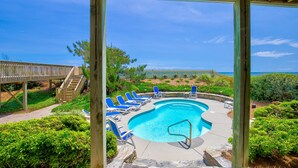 A pool area with blue lounge chairs, a wooden deck, and a view of the ocean. - Beachfront home with private heated pool, hot tub, & elevator (North Topsail Beach)