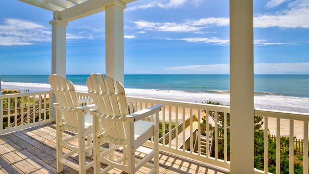 A wooden deck with two white Adirondack chairs overlooking a beach. - Beachfront home with private heated pool, hot tub, & elevator (North Topsail Beach)