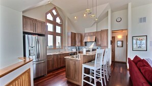 Una cocina moderna con armarios de madera, electrodomésticos de acero inoxidable y una isla central con asientos.