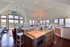 A spacious kitchen with a large island, wooden cabinets, and a built-in oven. - Waterfront home with private hot tub, sound view, shared pool, WiFi (Avon)