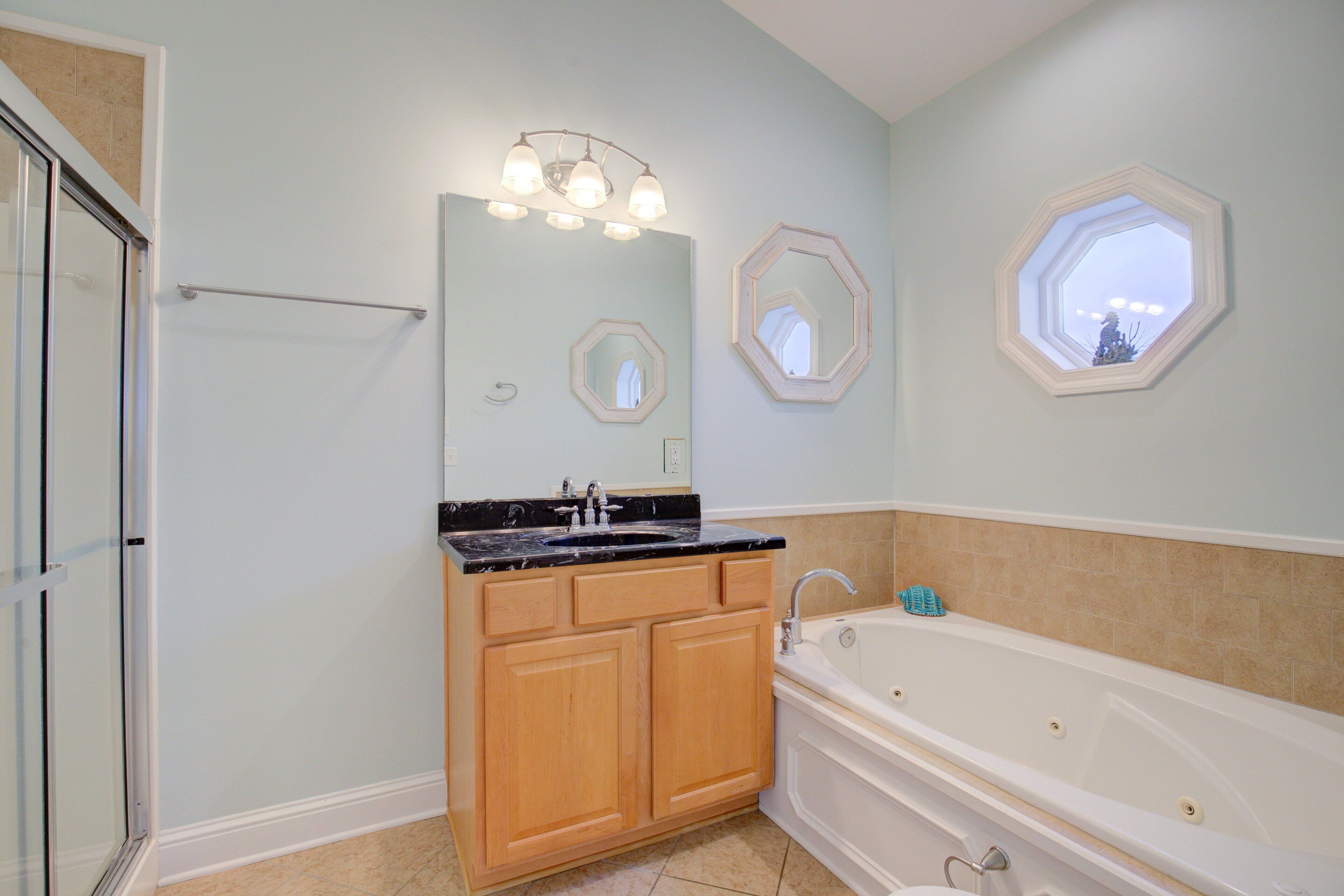 A bathroom with a bathtub, wooden vanity, and two wall-mounted mirrors.