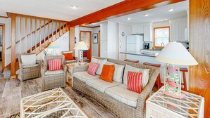 A spacious living area with a sofa, chairs, and a staircase.