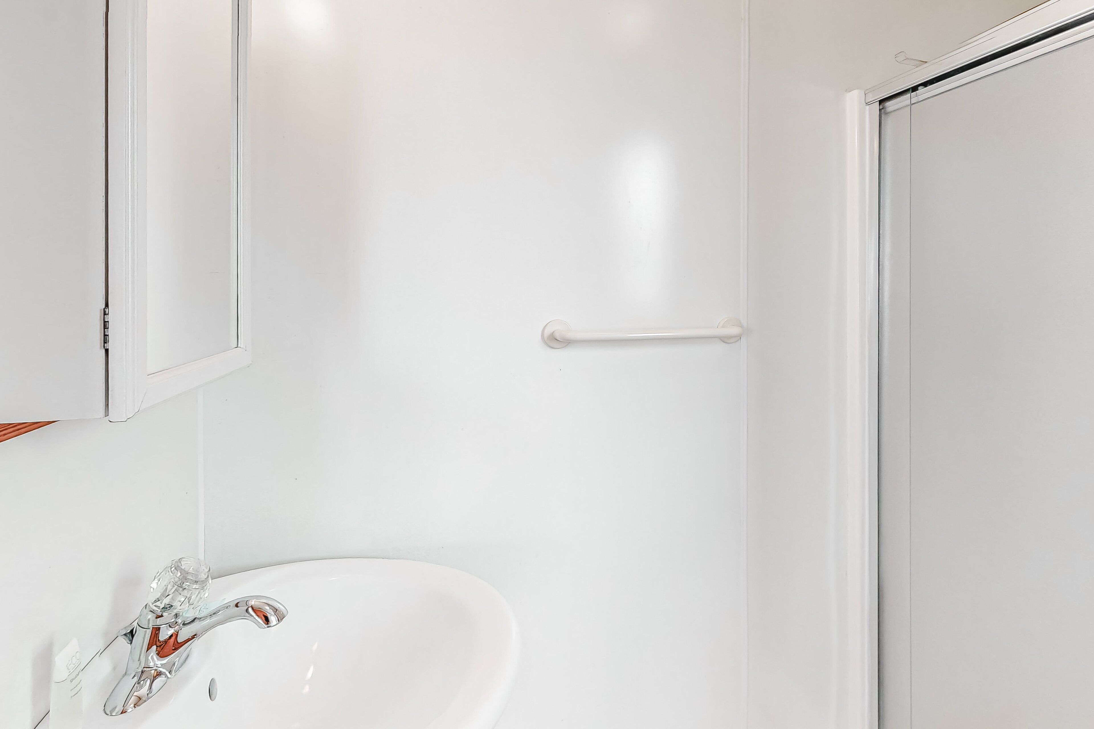 Un baño con un lavamanos blanco, un espejo y una puerta.