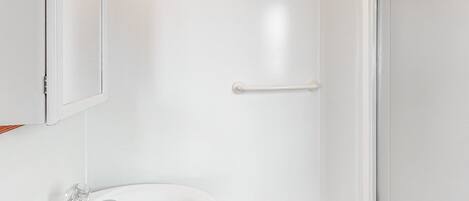 Un baño con un lavamanos blanco, un espejo y una puerta.