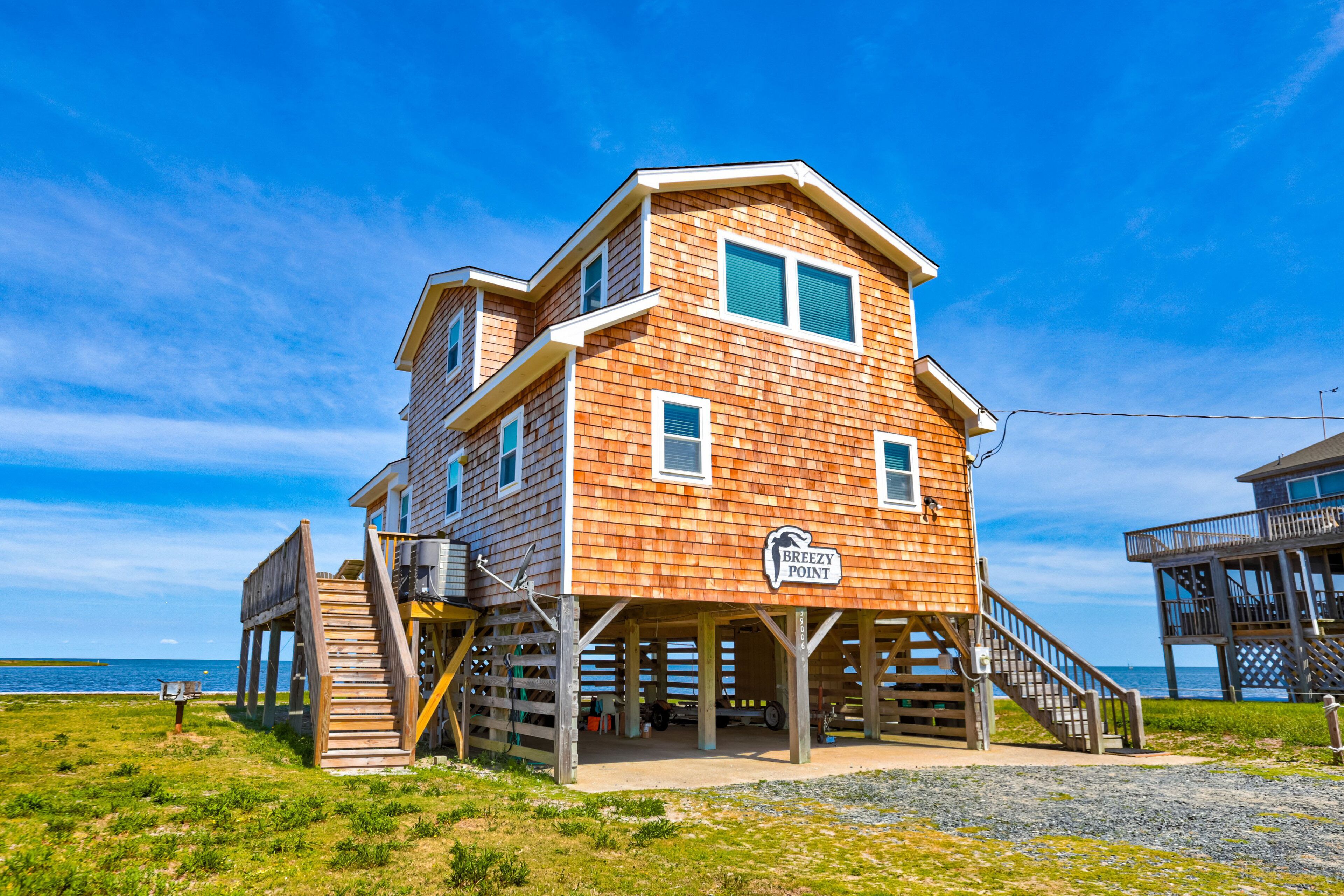 A wooden building with a sign reading "Breezy Point" on a beach with a clear sky.