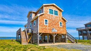 A wooden building with a sign reading "Breezy Point" on a beach with a clear sky.