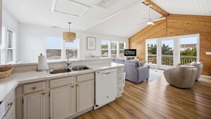 A spacious kitchen with white cabinetry, a dishwasher, and a large window. - Light-filled canal front home w/deck, washer/dryer, private hot tub, central A/C (Frisco)