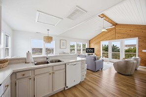 A spacious kitchen with white cabinetry, a dishwasher, and a large window.