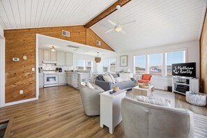 A spacious living area with a kitchen, a grey sofa, and a television.