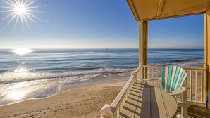A beach view from a covered deck with a table and chairs, overlooking the ocean. - Topsail Dunes condo - ocean-view balcony - beach access & beachfront pool (North Topsail Beach)