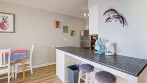 A kitchen with a granite countertop, a coffee maker, and a trash can. - Topsail Dunes condo - ocean-view balcony - beach access & beachfront pool (North Topsail Beach)