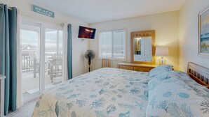 A bedroom with a bed, a TV, a dresser, a mirror, and a sign that says "BEACH". - Top-floor, oceanfront condo with stunning balcony views, pool, deck, central AC (Rodanthe)