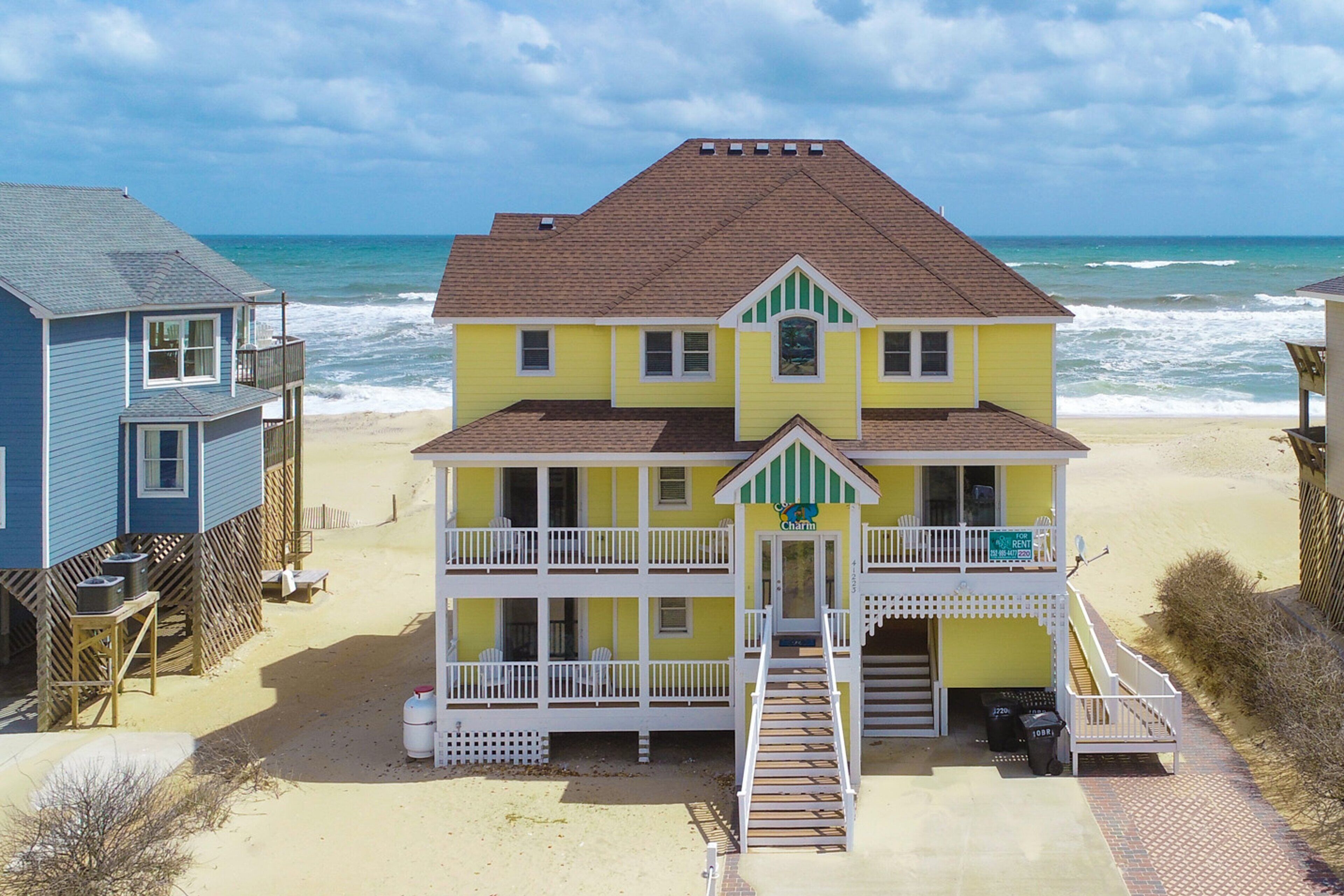 A two-story beach house with a balcony and a staircase leading to the entrance.
