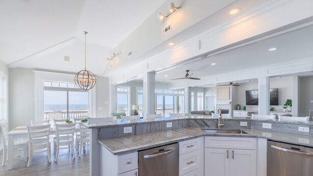 A modern kitchen with white cabinetry, stainless steel appliances, and a large island. - Beachfront, multi-level home with pool, beach access & private hot tub (North Topsail Beach)