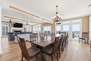 A spacious living area with a large dining table, multiple chairs, a fireplace, and a television. - Oceanfront home with volleyball, game room, pool, beach access & washer/dryer (North Topsail Beach)