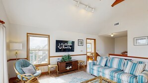 A living room with a television, a sofa, a chair, and a wooden coffee table. - Blue Seas #124-A: Soundside,Private Hot Tub, Roof Deck, Water/Lighthouse Views (Avon)
