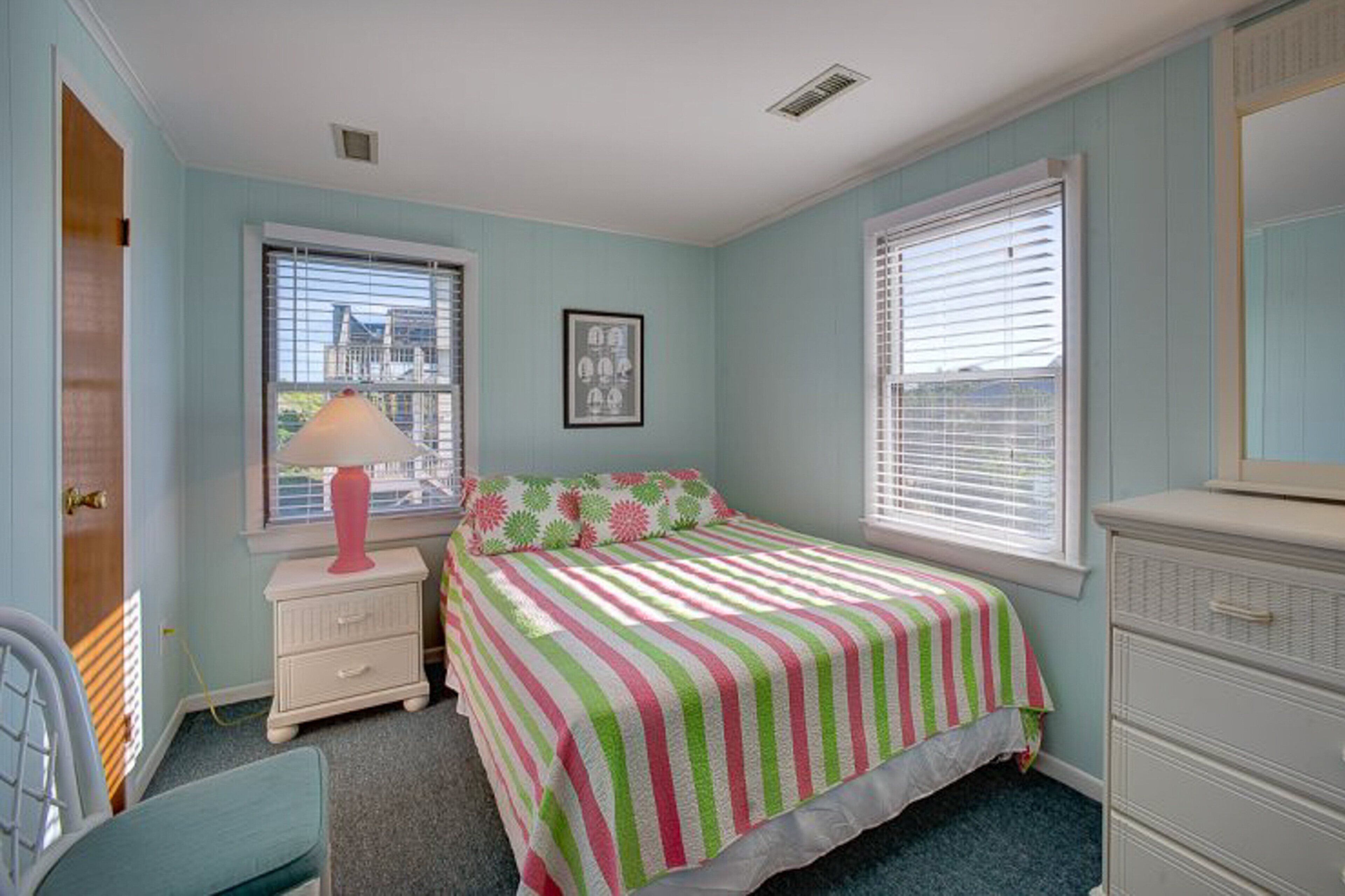 A bedroom with a bed, a nightstand, a dresser, and a window with blinds.